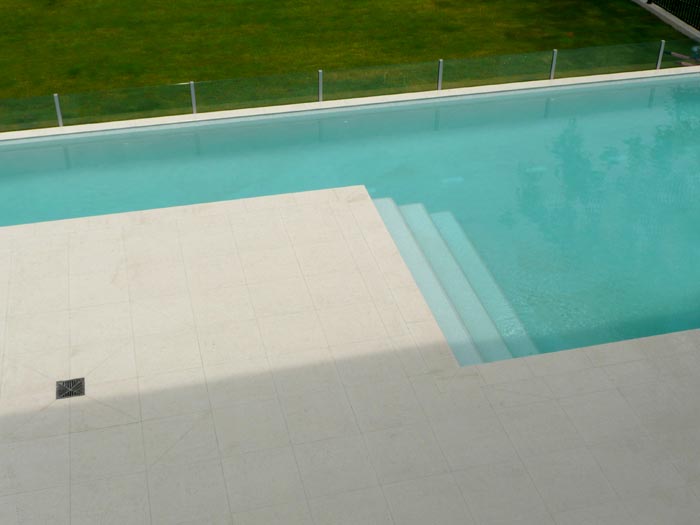 Light Travertino stone tile or pool paver shown in situ with matching coping