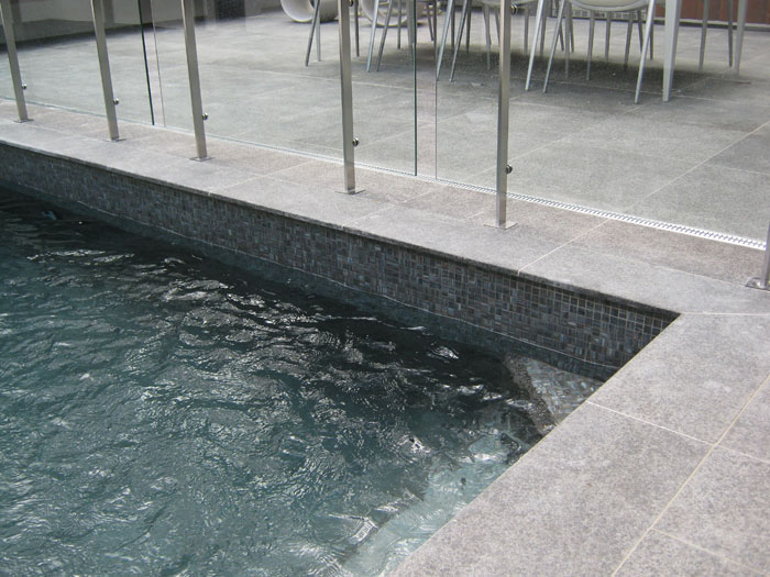 Black Granite stone tile or pool paver shown in situ with matching coping