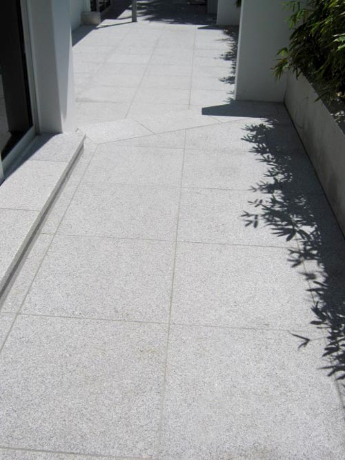 Closeup of Light Grey Granite stone tiles shown here being used for paving outside a house