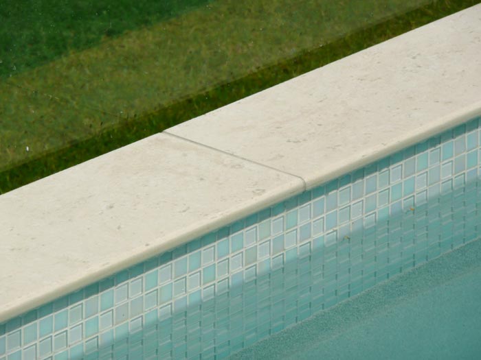 Light Travertino stone tile or pool paver shown in situ with matching coping