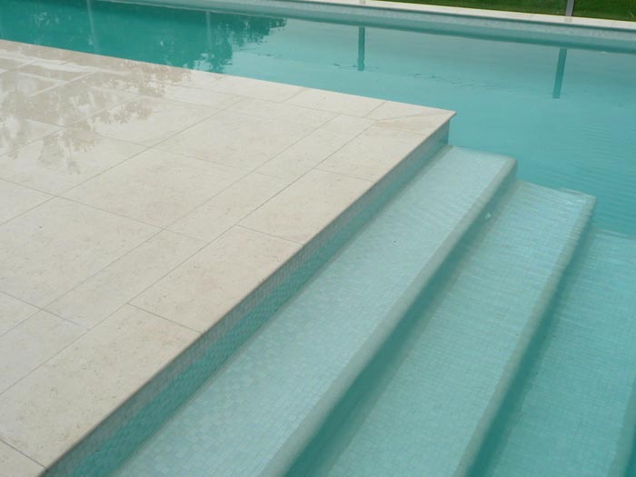 Light Travertino stone tile or pool paver shown in situ with matching coping