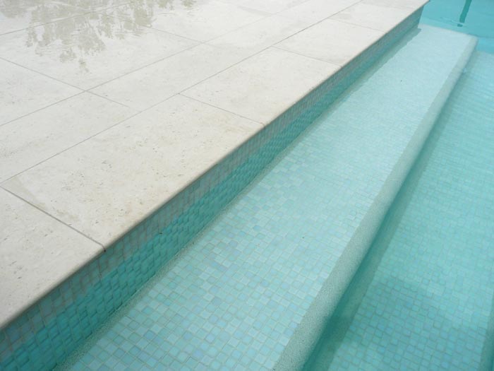 Light Travertino stone tile or pool paver shown in situ with matching coping