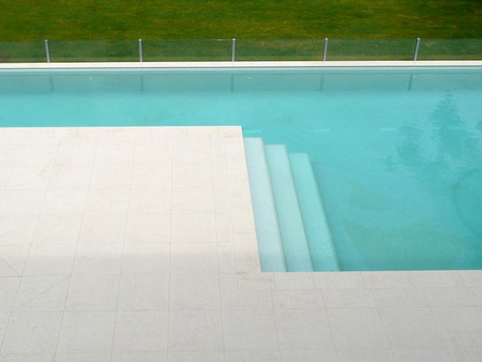 Light Travertino stone tile or pool paver shown in situ with matching coping