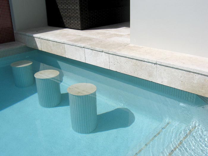 Travertine Linen tumbled unfilled stone tiles and coping around swimming pool with underwater stools