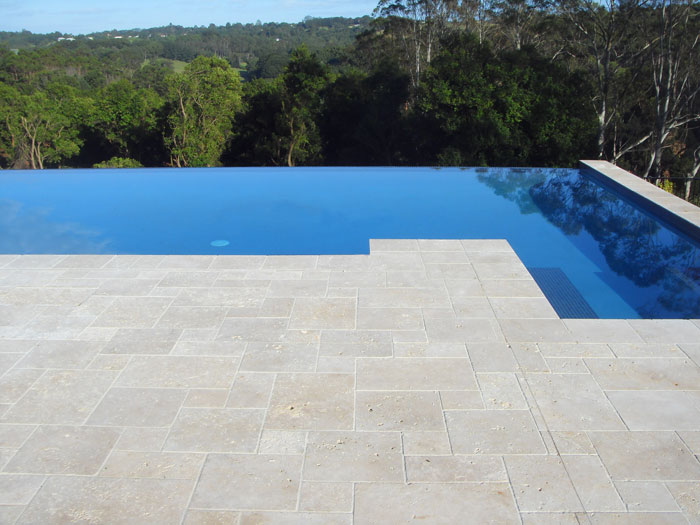 Travertine Linen stone tiles and coping around infinity edged swimming pool