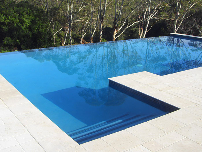 Travertine Linen stone tiles and coping around infinity edged swimming pool