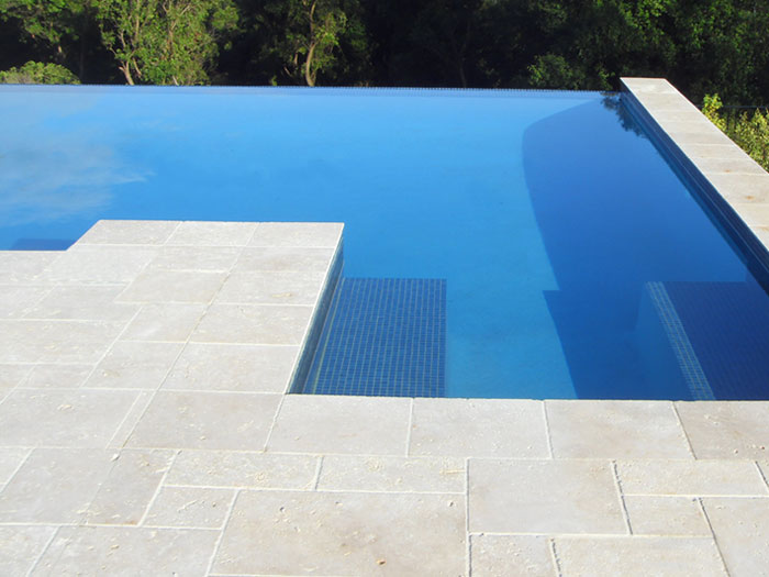 Travertine Linen stone tiles and coping around infinity edged swimming pool