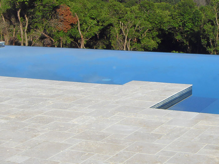 Travertine Linen stone tiles and coping around infinity edged swimming pool