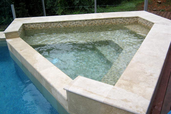 Travertine Linen stone spa pool tiling shown in situ with matching coping