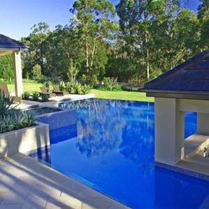 Nice exterior photo of a pool tiled with GC175 Sapphire Gold glass mosaic tiles