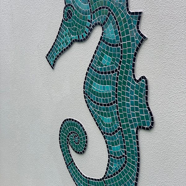 Wall feature of a green seahorse made from glass mosaics.