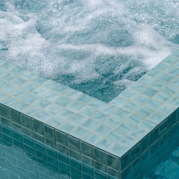 CMC572 Sea Mist Wavy is a soft, pale green textured ceramic mosaic used to fully tile this pool and spa.