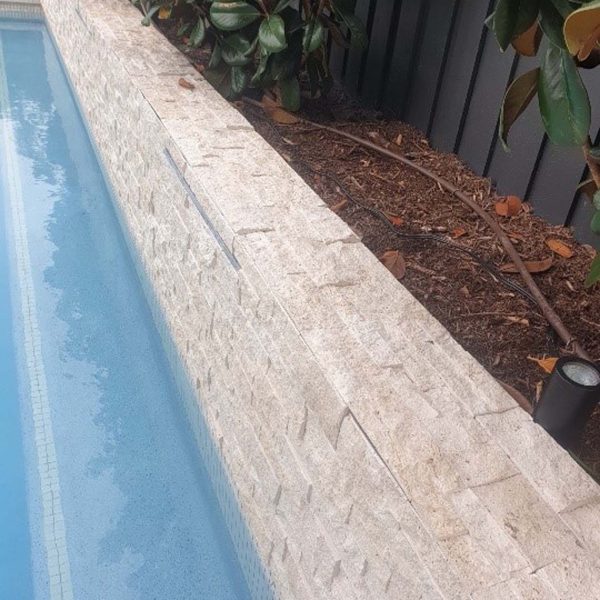 SS700 Linen travertine stacked stone feature wall with Latte Porcellano poolside paving tiles and Luna mosaic waterline tiles