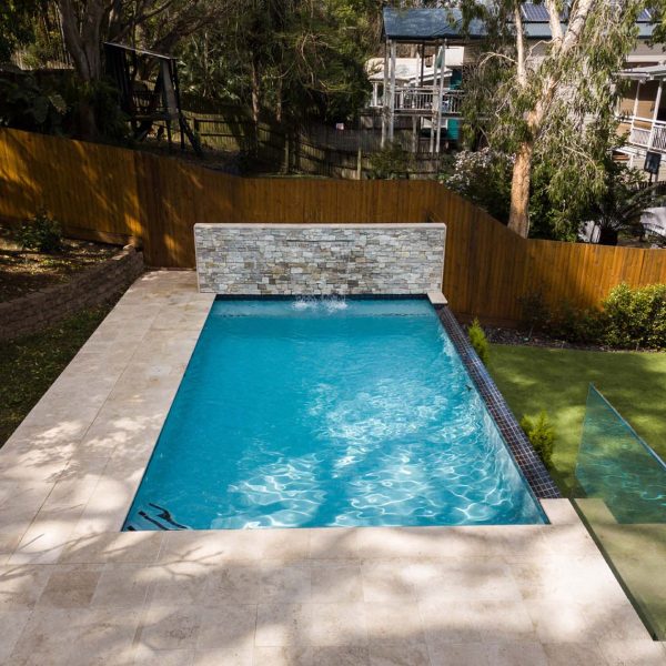 Linen Travertine pool coping, surrounds and steps with Black ceramic waterline tile and Thredbo stone cladding